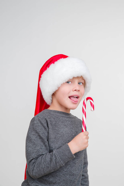 Little emotional blond boy in a festive red hat. Little Santa Claus. - Fotoğraf, Görsel