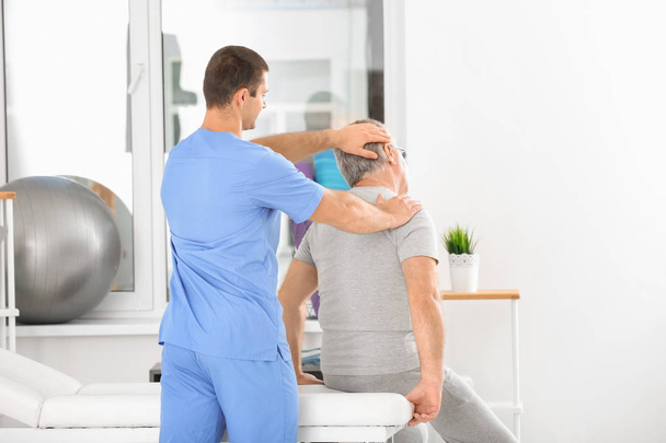 Physiotherapist working with senior patient in modern clinic - Photo, Image