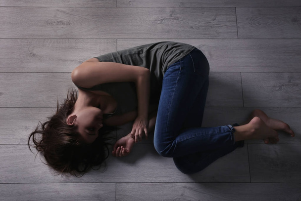 Battered young woman lying on floor - Foto, afbeelding