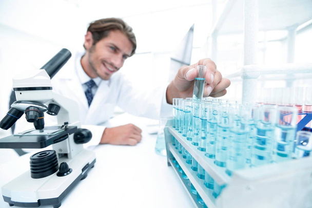 Chemist looking at test-tubes with blue liquids - Фото, изображение