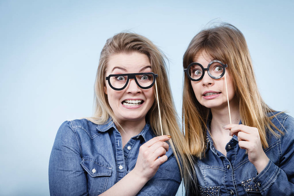 Two happy women holding fake eyeglasses on stick - Фото, зображення