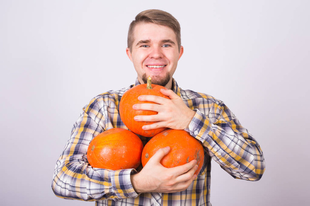 portrait of a young farmer holding a pumpkins on a light background studio - Photo, Image