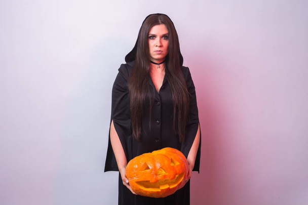 Donna come strega è in piedi con la zucca nello studio. Halloween e il concetto di carnevale
 - Foto, immagini