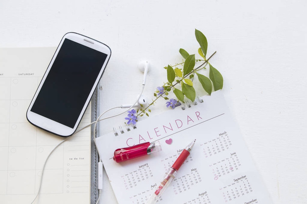 ноутбук с календарным планировщиком и мобильным телефоном для финансовых на белом столе
 - Фото, изображение