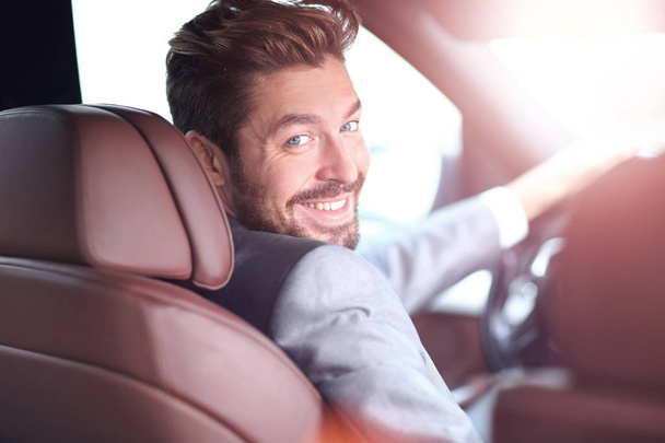 Porträt eines gut aussehenden lächelnden Geschäftsmannes am Steuer seines Autos - Foto, Bild