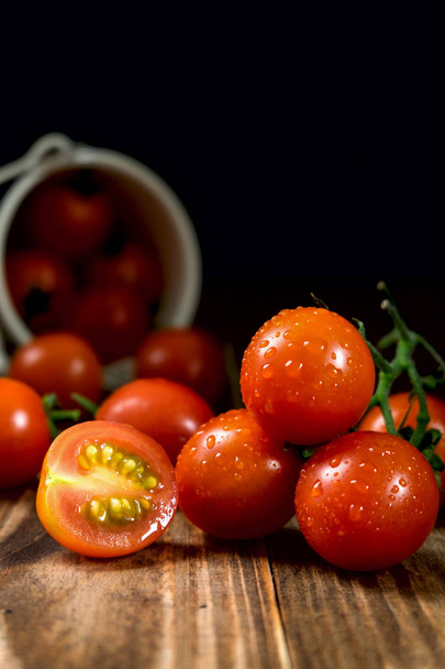 Ripe cherry tomatoes in a bucket on a wooden background. Rustic  - Fotó, kép