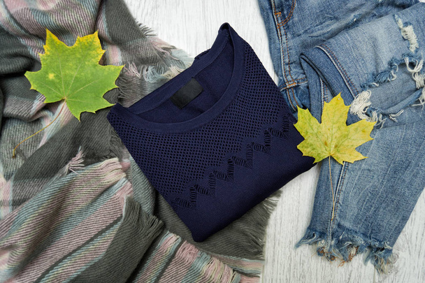 Μπλε πουλόβερ, κασκόλ, τζιν και maple φύλλα. Μοντέρνα έννοια - Φωτογραφία, εικόνα