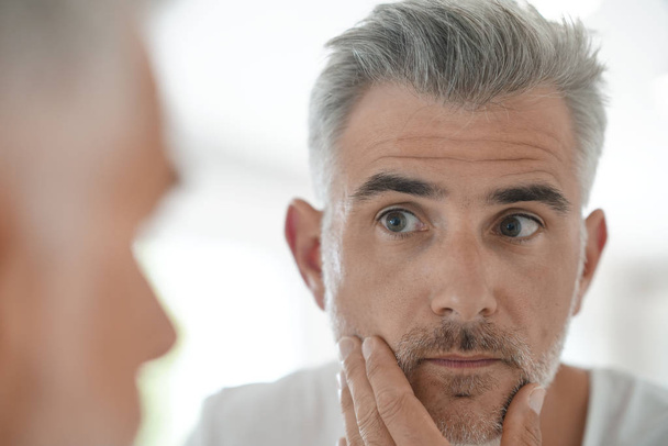 Middle-aged man applying cosmetic - Фото, изображение
