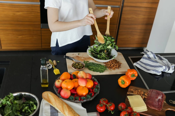 Young woman mixing green salad - Foto, afbeelding