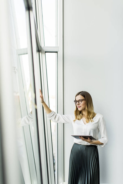 Молода бізнес-леді стоїть провід планшет в офісі
 - Фото, зображення