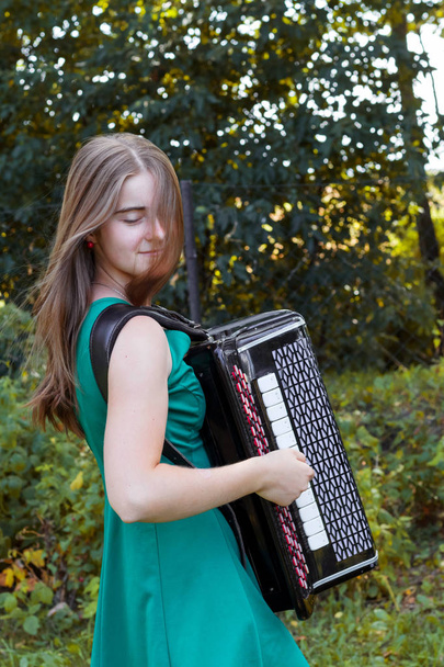 Dziewczyna muzyk gra rosyjski bayan (przycisk akordeon) i śpiew. - Zdjęcie, obraz