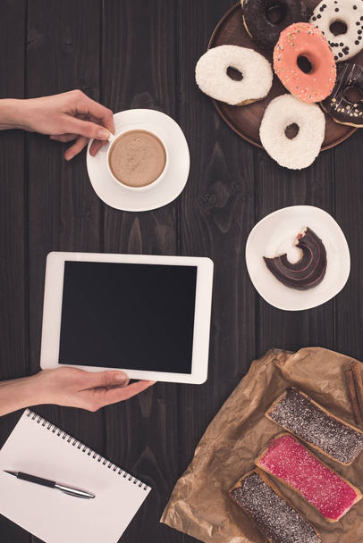 person with coffee, digital tablet and donuts  - Foto, afbeelding