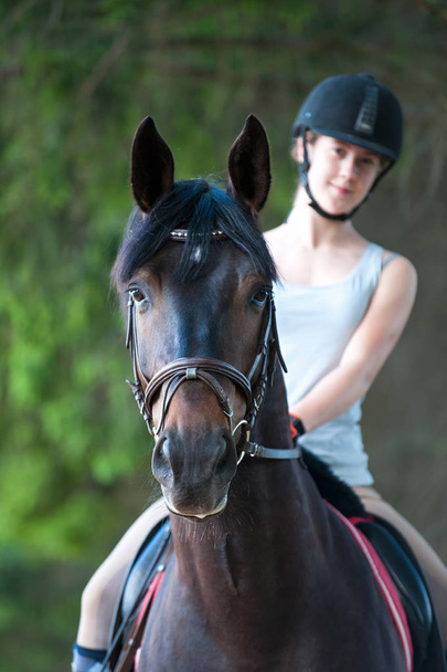 Портрет черной лошади с девочкой-подростком на ней
 - Фото, изображение