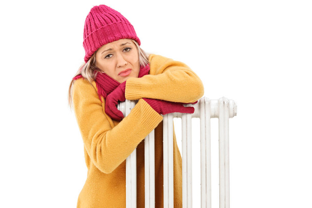 Freezing young woman leaning on a radiator - Φωτογραφία, εικόνα