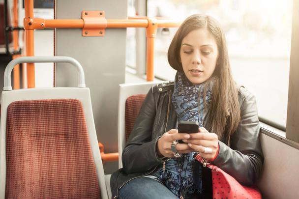 Young girl uses a mobile phone in the city bus - Foto, Bild