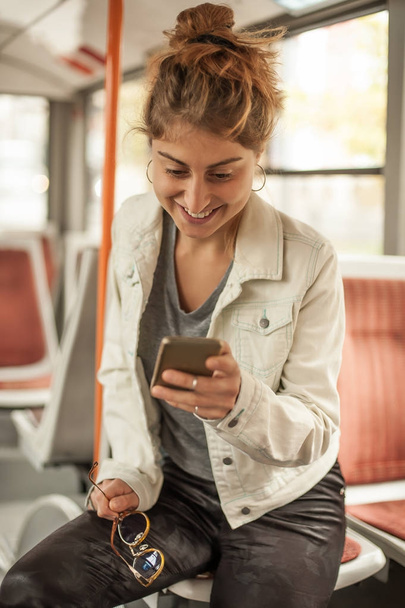 Young girl uses a mobile phone in the city bus - Foto, Bild