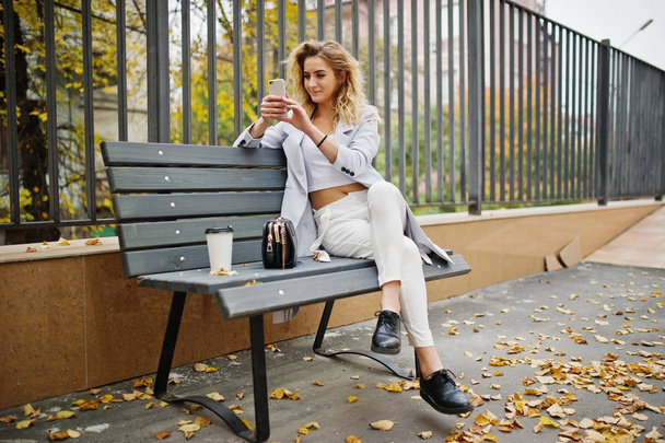 Стильная кудрявая блондинка модель девушки носить на белом с чашкой кофе
 - Фото, изображение