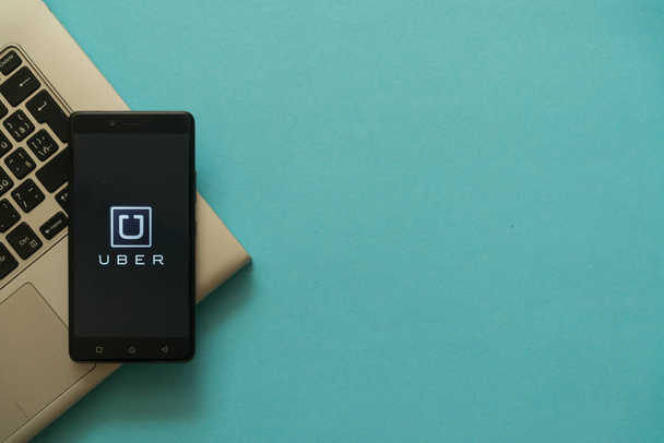 Uber logo on smartphone placed on laptop keyboard. - Fotó, kép