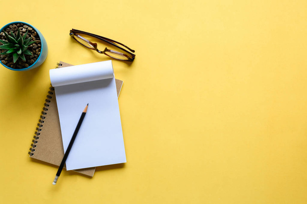 notebook and pencil on yellow desk - Φωτογραφία, εικόνα