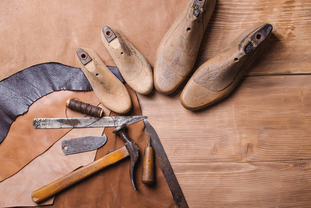 Cobbler tools in workshop on the wooden table . Top view. - 写真・画像