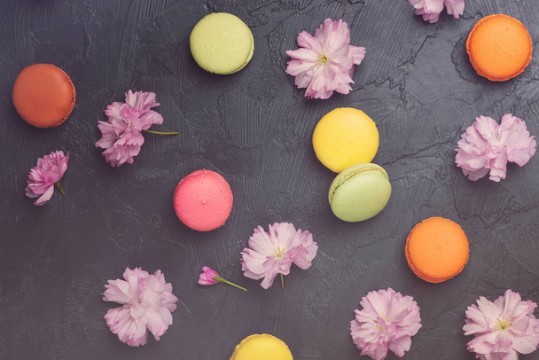 Colorful macarons with spring sakura flowers on black backround. Top view. - Foto, immagini