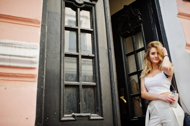 Stylish curly blonde model girl wear on white posing against old - Foto, imagen