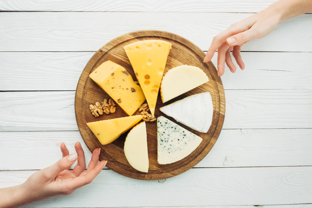female hands and arranged types of cheese - Photo, Image