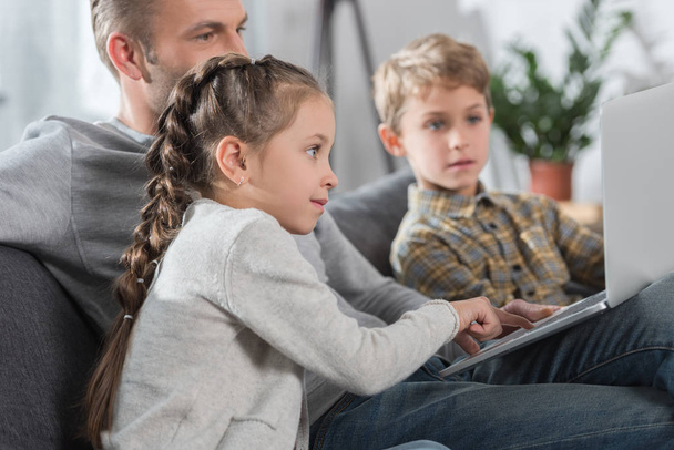 Pai sentado com crianças e laptop
  - Foto, Imagem
