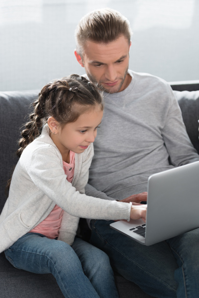 Isä ja tytär katsomassa kannettavaa tietokonetta
 - Valokuva, kuva
