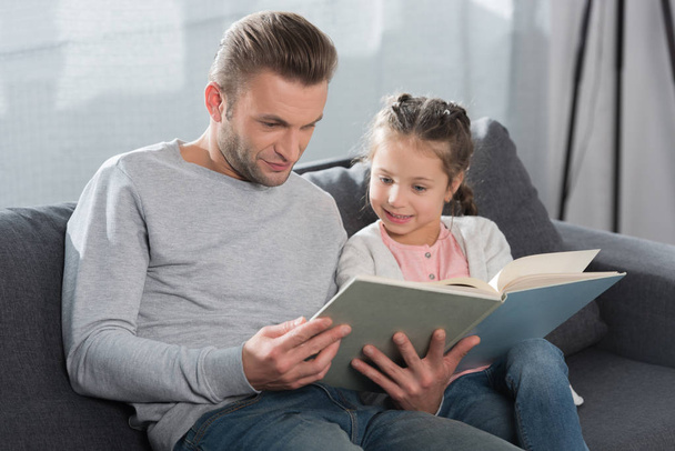 Father teaching daughter read at home - Photo, image