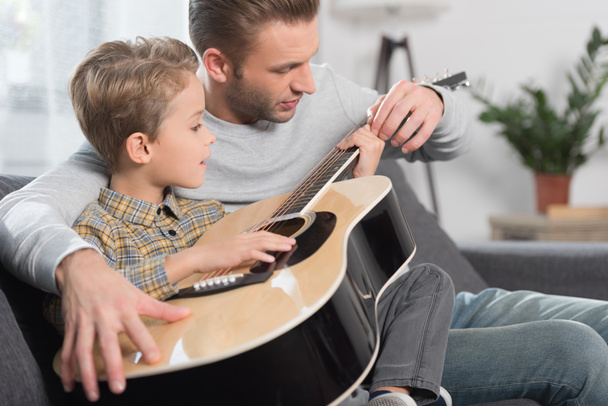 Father teaching son play guitar - Valokuva, kuva