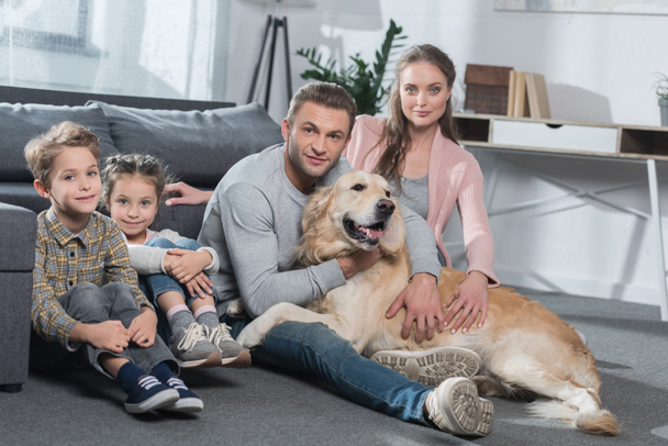 Family and dog sitting on floor - 写真・画像