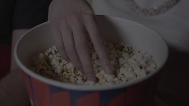 Kezébe veszi a pattogatott kukorica, egy papír üveg a moziban - Felvétel, videó