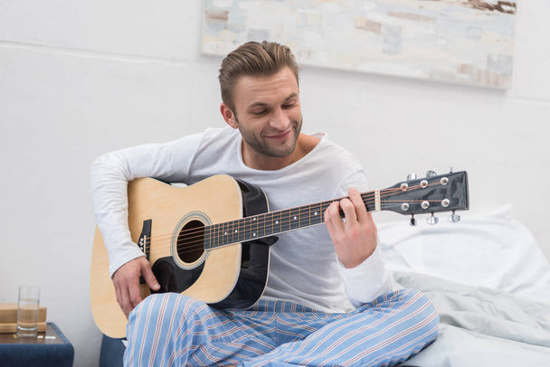 man playing guitar on bed - Foto, Bild