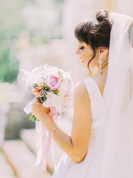 The close-up back view of the charming bride holding the wedding bouquet of colourful peonies. - Foto, Imagen
