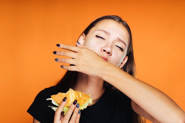 young beautiful girl wants to lose weight, but eats a harmful high-calorie burger - Fotografie, Obrázek