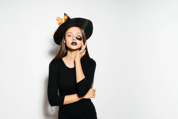 young sexy cheerful gothic girl celebrating halloween, dressed in a witch, in a big black hat, posing - Valokuva, kuva