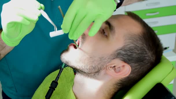 man sitting on dental chair while his dentist fixes his teeths - Footage, Video