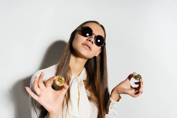 young successful modern girl in sunglasses, holds in hands golden bitcoins - Photo, Image