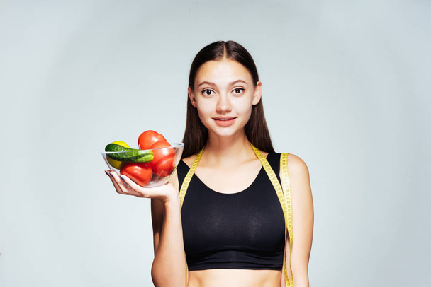 Siyah top bir güzel kız, kilo vermek istiyor bir genç tutan bir tabak yararlı sebze ve meyve ile onun elinde - Fotoğraf, Görsel