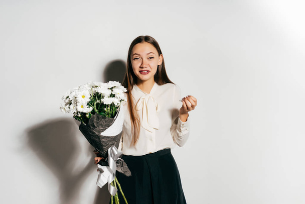 young beautiful girl holding a large bouquet of white flowers and sneezes because she is allergic - Photo, Image