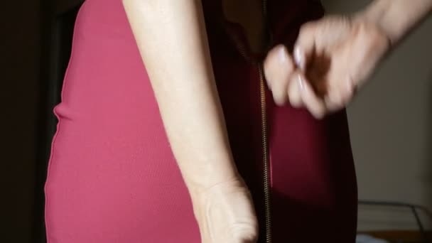 Γυναικεία δάχτυλα Στερεώστε ένα φερμουάρ στην κόκκινη φούστα. ορατή κιλότες και τους γλουτούς. γκρο πλαν, λεπτομέρειες. - Πλάνα, βίντεο