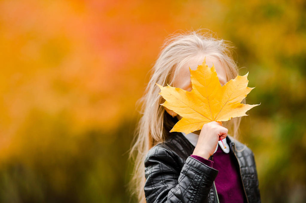 Портрет чарівної маленької дівчинки з жовтим листям букет восени на скутері
 - Фото, зображення