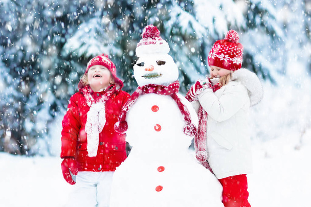 Дети строят снеговика. Дети в снегу. Зимнее веселье
. - Фото, изображение