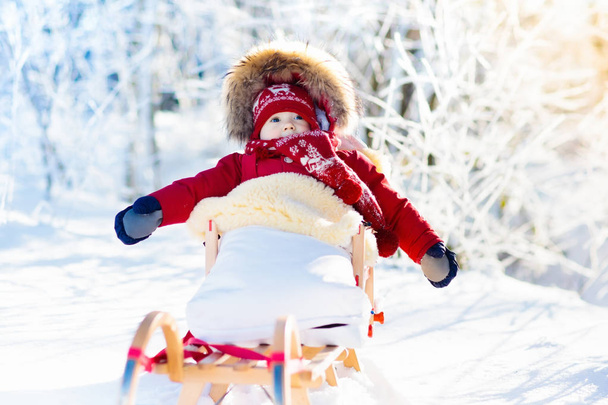 Slee en de sneeuw pret voor kinderen. Baby rodelen in winter park. - Foto, afbeelding