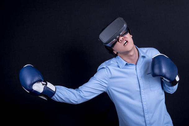 junger Mann mit Virtual-Reality-Brille und Boxhandschuhen - Foto, Bild