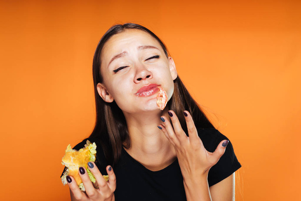 young beautiful girl wants to lose weight, eagerly eats a harmful high-calorie hamburger - Fotó, kép