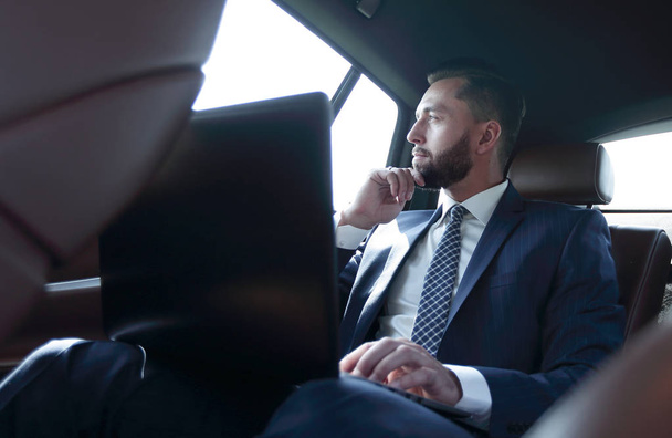 businessman working with laptop and looking out the window of a car - Foto, Imagen