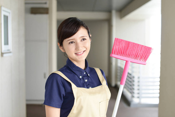 Smiling Asian housewife with a broom - Photo, Image