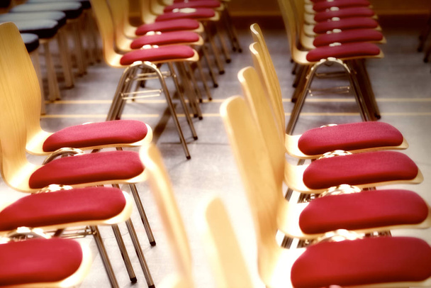 Rangées floues de chaises vides en bois dans un grand hall d'assemblage.Chaises vides dans la salle de conférence.
. - Photo, image